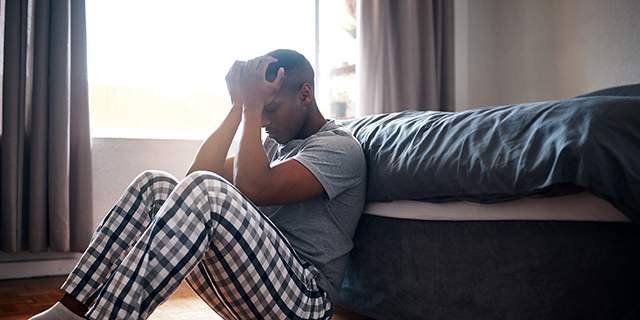 Man sitting by his bed during the COVID-19 pandemic.