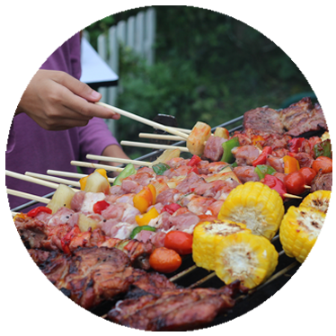 Woman cooking kabobs and corn on the grill